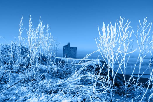 a seasonal snow covered view of atlantic ocean and ballybunion castle beach and cliffs on a frosty snow covered winters day