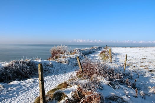 a seasonal snow frosty covered slippery cliff walk with a blue cloudy sky background