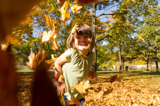 Girl playing outside with the colorful foliage in autumn