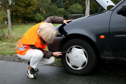 Senior citizen checks car tires