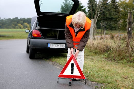 Senior citizen sets up warning triangle