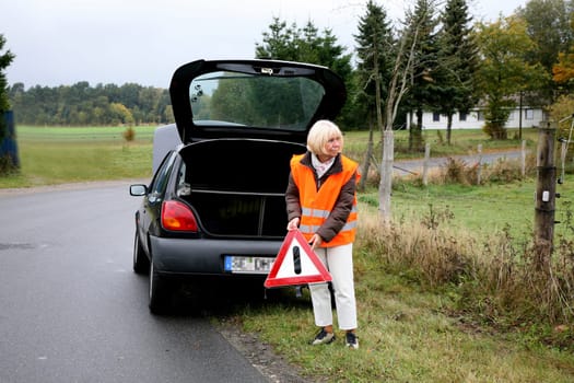 Senior citizen sets up warning triangle