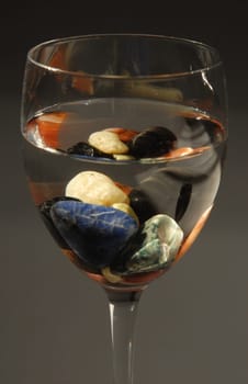 Glass with colored stones and water. Concepts of altenative therapies, zen life and harmony.