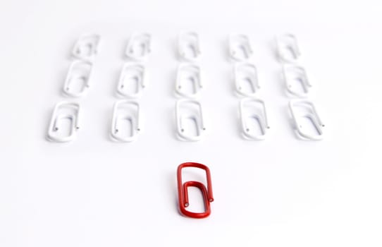 Conceptual idea of leadership. Red clip in focus, leading a group of aligned white clips
