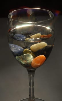 Colored stones in a glass of water. Concepts of altenative therapies, zen life and harmony.