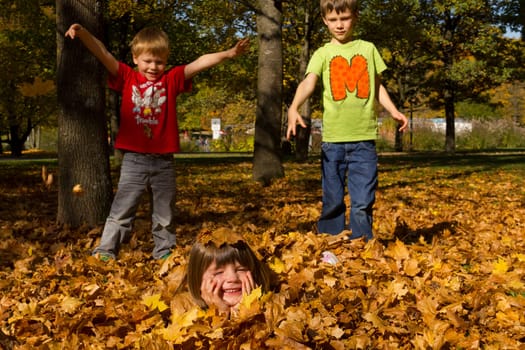 Children playing with leaves in autumn