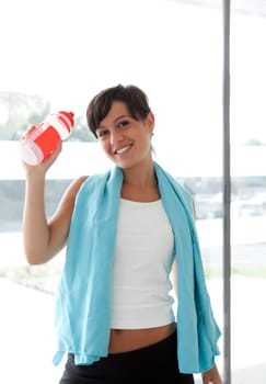 girl with sport water bottle in hand and towel after workout