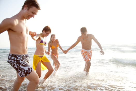 group of young people having fun, running in the surf