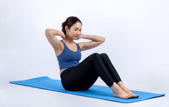 Asian woman in sportswear doing crunch on exercising mat as workout training routine. Attractive girl in pursuit of healthy lifestyle and fit body physique. Studio shot isolated background. Vigorous