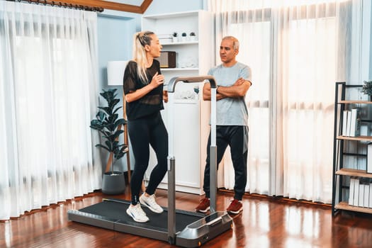 Active senior couple running on tread running machine at home together in full body shot as fitness healthy lifestyle and body care after retirement for pensioner. Clout