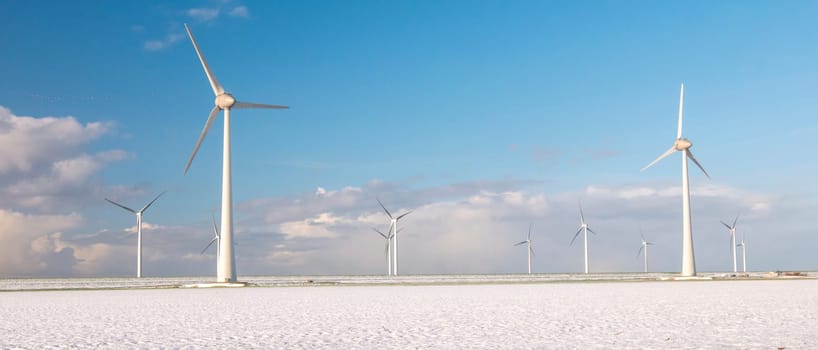 Windmill turbines n the Netherlands during winter with snow at the meadow field, windmill park during winter weather