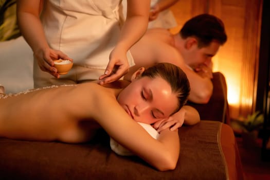 Couple customer having exfoliation treatment in luxury spa salon with warmth candle light ambient. Salt scrub beauty treatment in Health spa body scrub. Quiescent