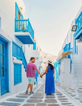 Romantic couple of men and women at the street of Mykonos Greek village in Greece, colorful streets of Mikonos village. in the morning during vacation in Greece