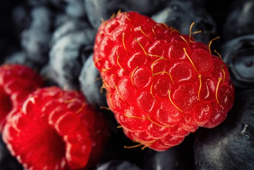 Abstract colorful berries, extreme macro. Wild ripe forest raspberries, blueberries. Fresh fruits, harvest background. High quality photo