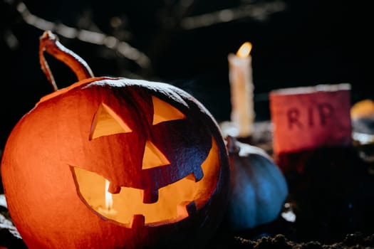 Fearful symbol of Halloween - Jack-o-lantern on ground cemetery at night. Scary smiling head of pumpkins close-up. Glowing face, trick or treat.