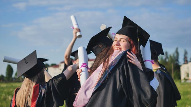 Two college graduates hugging on a sunny day