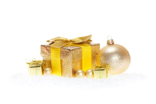 Package with bow,golden balls lying in the snow against white background