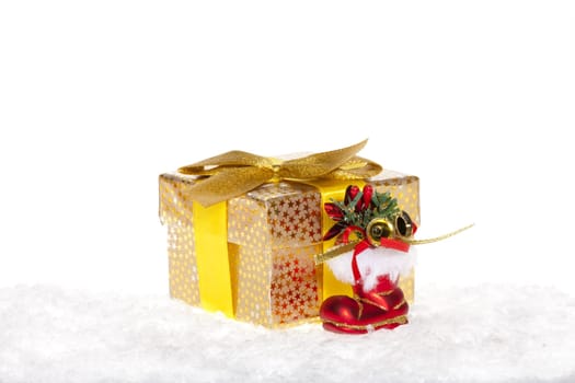 Package with bow,red Santa boots lying in the snow against white background