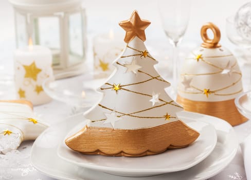 Festive table for Christmas with small tree in white and golden tones