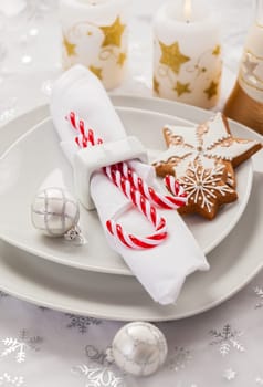 Place setting in white for Christmas with gingerbread cookie and candy cane