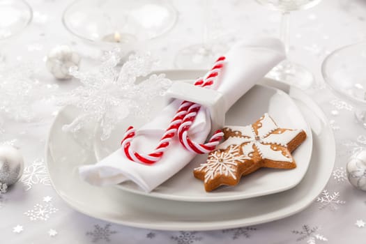 Place setting in white for Christmas with gingerbread cookie and candy cane