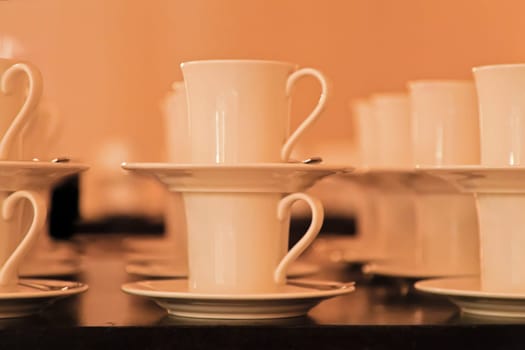 Side elevation rows Cups Saucers stacked in pairs, warm background. Shot location Bombay studio, India rendered soft focus