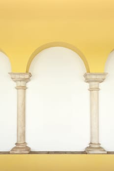 Two marble columns embedded in the wall topped by an arch painted in yellow, Elvas, Portugal
