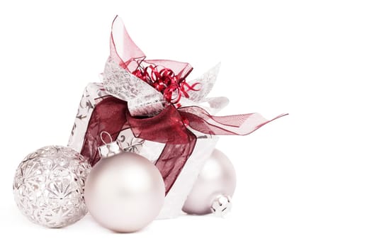 Silver Christmas gift with red ribbons and baubles on white background