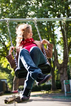 Low angle shot of beautiful young woman on swing in playground.