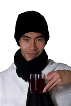 asian man in winter clothes holds an glas in his hand filled with punch or red tea