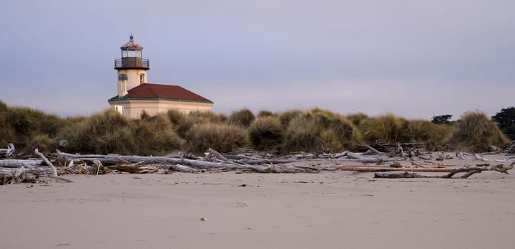 Beach driftwood at low tide in front of Coquille River Lighthouse in Oregon