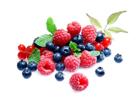 Assortment of fresh blueberries, raspberries and redcurrants garnished with mint in a random pile isolated on white