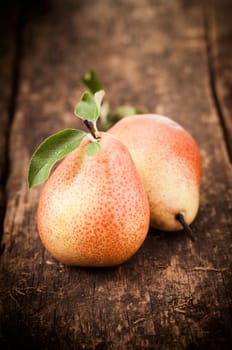 Freshly harvested ripe red and yellow pears with leaves lying on an old grungy wooden table top