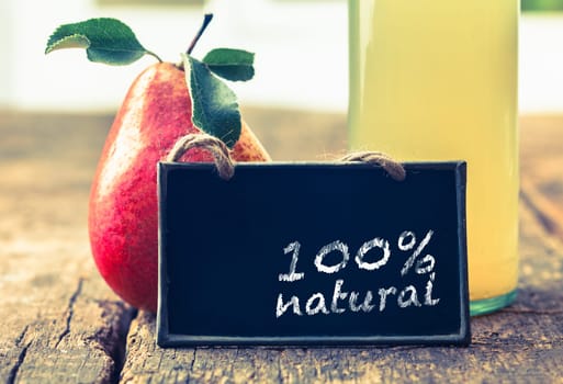 Natural pear juice in a glass bottle on display at a farmers market with a sign saying that it is 100 percent pure
