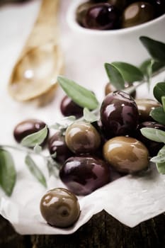 Closeup of fresh black olives and leaves in the kitchen for use as a cooking or salad ingredient
