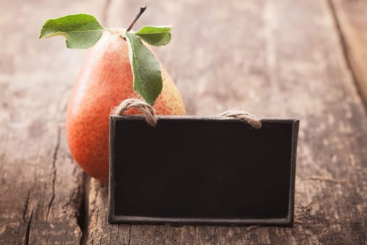Fresh ripe red and yellow pear with a blank blackboard slate for your text on an old wooden table