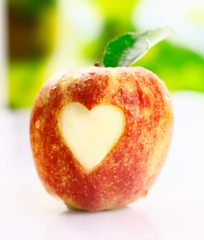 A juicy fresh ripe red apple with an incised heart shape in the skin conceptual of I love apples