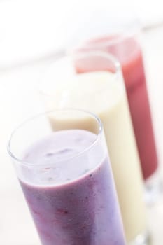 High angle view of a row of assorted fruit smoothies or milkshakes blended with healthy yoghurt in tall glasses with shallow dof