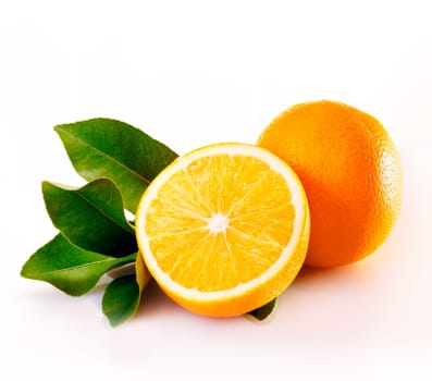 A whole and halved juicy orange showing pulp and segment detail with green citrus leaves on a white background