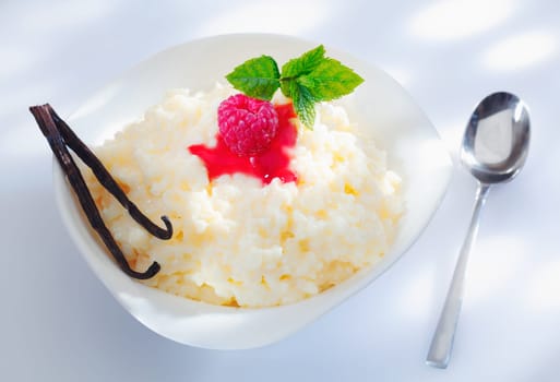 A serving of delicious rice pudding cooked with milk or cream and garnished with raspberry and vanilla pods