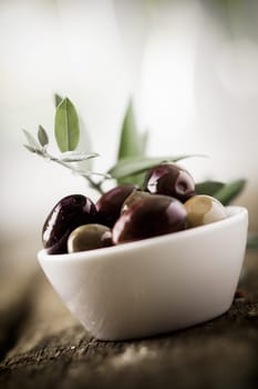 Tilted view of a bowl of fresh black olives with shallow dof and copyspace