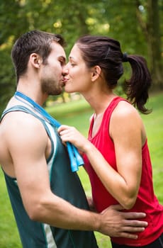 Young happy fitness couple kissing - woman put skipping rope around men's neck