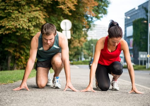 Young sport couple in starting postion prepared to compete and run