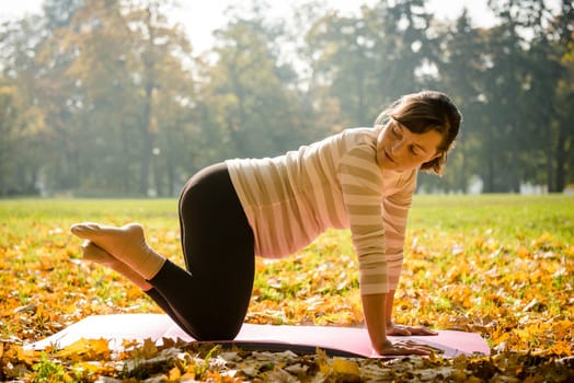 Fitness pregnant woman exercising outdoor in autumn nature
