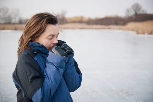 Young woman in winter nature trying to warm her frozen hands
