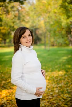 Young happy smiling pregnant woman outdoor in autumn nature
