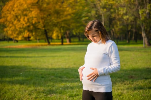 Young happy smiling preagnant woman outdoor holding belly