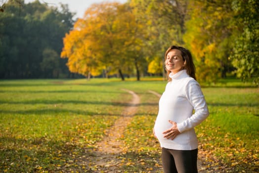 Young happy smiling pregnant woman outdoor in autumn nature