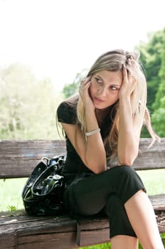 Young beautiful woman siting on bench in park in depression