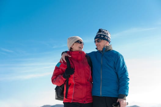 Senior couple outdoor portrait- happy mature man and woman in winter snowy landscape